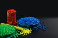 Blue, yellow, red granules of polypropylene, polyamide in a test tube and a petri dish. Black background. Plastic and polymer indu Royalty Free Stock Photo