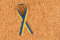 Blue and yellow ribbon in colours of Ukrainian flag over wheat grain as background with copy space Royalty Free Stock Photo