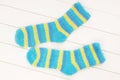 Blue and yellow socks are on white wooden background, isolated striped terry multicoloured socks