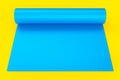 Blue yoga mat or lightweight foam camping bed roll pad isolated on yellow.