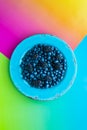 Blueberries and blackberries on a bright blue plate against a vibrantly colourful background.