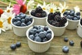 Blueberries and blackberries garden daisies on rustic wood table