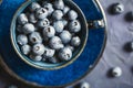 Blueberries in a ceramic cup on a worn dark blue background. Wild berry of Northern Europe. Healthy ripe berries