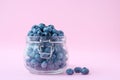 Blueberries in a glass bowl on a pink background, a berry in a glass jug. Vegetarian food concept