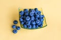 Blueberries on glass plate on yellow background Royalty Free Stock Photo