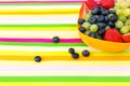 Blueberries, grapes and strawberries in a bowl on a striped tabl
