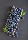 Blueberries with green leaves in old wooden dish Royalty Free Stock Photo