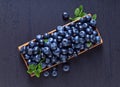 Blueberries with green leaves in wooden dish Royalty Free Stock Photo