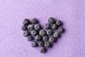 Blueberries heart on purple from above