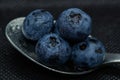 Blueberries Macro closeup photo of superimposed on top of each other and tiled in a teaspoon on a dark background glistening in