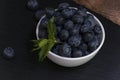 Blueberries with mint leaves in a small white bowl. On a black granite board. Yummy Royalty Free Stock Photo