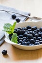 Blueberries and mint in a white bowl on wooden background Royalty Free Stock Photo