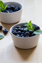 Blueberries and mint in white bowls on a wooden background Royalty Free Stock Photo