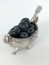 Blueberries in an old silver bowl decorated with swans. Silver antique spoon. White background.