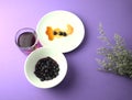 Blueberries, pulp in syrup in plate, blueberry juice on purple background with dried purple flowers. Royalty Free Stock Photo