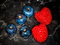 Blueberries and raspberries laid out on a dark plate Royalty Free Stock Photo