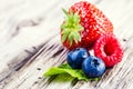 Blueberries, raspberries, strawberries on wooden background.