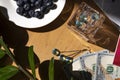 Blueberries in a white plate on a wooden table against the background of American dollars, magazines and plants with green leaves Royalty Free Stock Photo