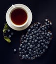 Blueberries on a wooden dish, cup of tea, and dried melis leaves Royalty Free Stock Photo