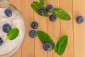 Blueberries with yogurt and mint leafs on wooden table.