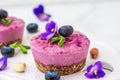 Blueberry and acai vegan cashew cakes with fresh berries, edible flowers, mint, nuts. healthy vegan food concept