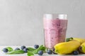 Blueberry, banana and spinach smoothie or milkshake in a glass with fresh fruits and berries. Healthy drink