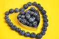 Blueberry heart shape symbol concept for healthy eating and lifestyle. Isolated on yellow background. Royalty Free Stock Photo