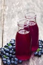 Blueberry juice in glass bottles on wooden table Royalty Free Stock Photo