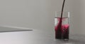 Blueberry juice pour into water in highball glass on kitchen countertop