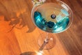 Blueberry martini on wooden table in sunny setting. Blue martini. Summer set