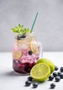 Blueberry Mojito Or Lemonade With Lime, Ice And Mint In A Glass On A Light Background With Berries And Fruit. The Concept Of A