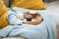 Blueberry muffin with coffee, sugar and milk on wooden tray and comfy sofa with blue wool knit blanket and yellow cushions Royalty Free Stock Photo