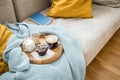 Blueberry muffin with coffee, sugar and milk on wooden tray and comfy sofa with blue wool knit blanket, yellow cushions and book Royalty Free Stock Photo