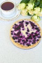 Blueberry pie, cup of tea and white roses on a white background - vertical