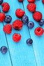 Blueberry and raspberries on blue wooden background