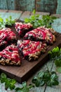 Blueberry scones with raspberry jam topping on oak cutboard with blueberry leaves on old painted wood background