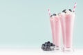 Blueberry smoothies with straws, berries in bowl, whipped cream in high glass on white wood table and pastel blue wall, copy space Royalty Free Stock Photo
