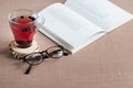 Blueberry tea in a clear glass cup on a round wooden stand with glasses