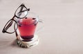 Blueberry tea in a glass cup and with glasses in a brown frame on it,