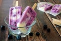 Blueberry vanilla popsicles in a clear bowl against wood