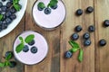 Blueberry yogurt with fresh berries and mint leaves. Two glasses of yogurt and a lot of scattered blueberries