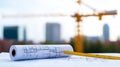Blueprints and construction plans rolled out with measuring tape showcasing construction site in background image captures Royalty Free Stock Photo