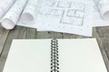 Blueprints rolls with plans and notepad on gray wooden table