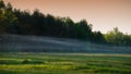 Bluish streak of smoke from a fire against the background of a forest and meadow in the evening panoramic landscape in the Royalty Free Stock Photo