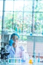 Blur Asian woman scientist, researcher, technician, or student conducted chemistry research and sitting after  glass board in Royalty Free Stock Photo
