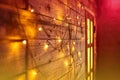 Blur Christmas lights on wooden planks and door. Bright glowing garland. New Year lights background. Yellow red color