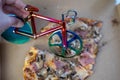 blur effect, woman hand cutting delicious pizza in carton box on table, bicycle pizza cutter knife on cheese in cardboard