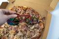 blur effect, woman hand cutting delicious pizza in carton box on table, bicycle pizza cutter knife on cheese in cardboard