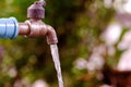 Water flowing from old steel faucet in outdoor space Royalty Free Stock Photo