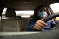 Blur male wearing a face mask, black glasses, and a black hat. Closeup a man driving hands to hold the steering wheel to control